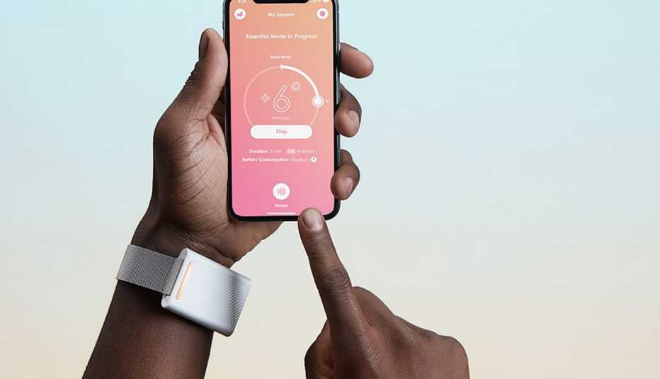 Mano lleva puesta una pulsera blanca y se ve una aplicación abierta en un teléfono móvil