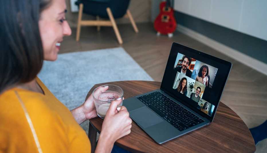 Mujer que usa una computadora portátil para una videoconferencia con varias personas
