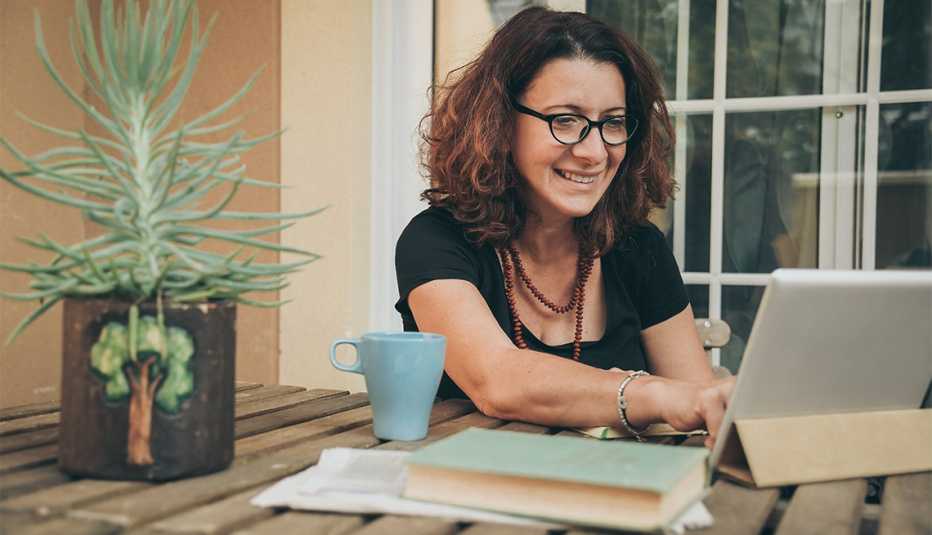 Mujer en casa con libros, periódicos y una tableta electrónica