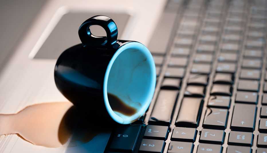 Taza de café derramada sobre el teclado de una computadora