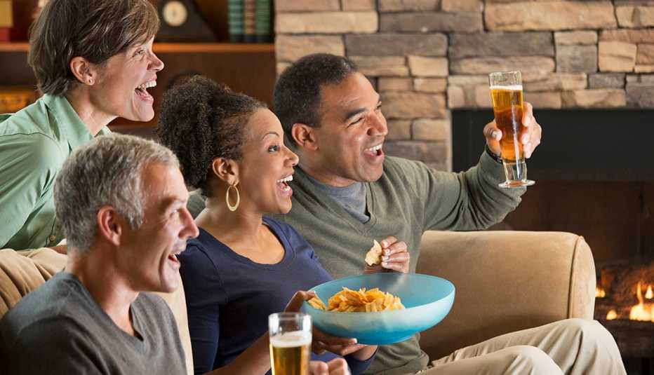 Dos parejas beben cerveza mientras ven un evento deportivo