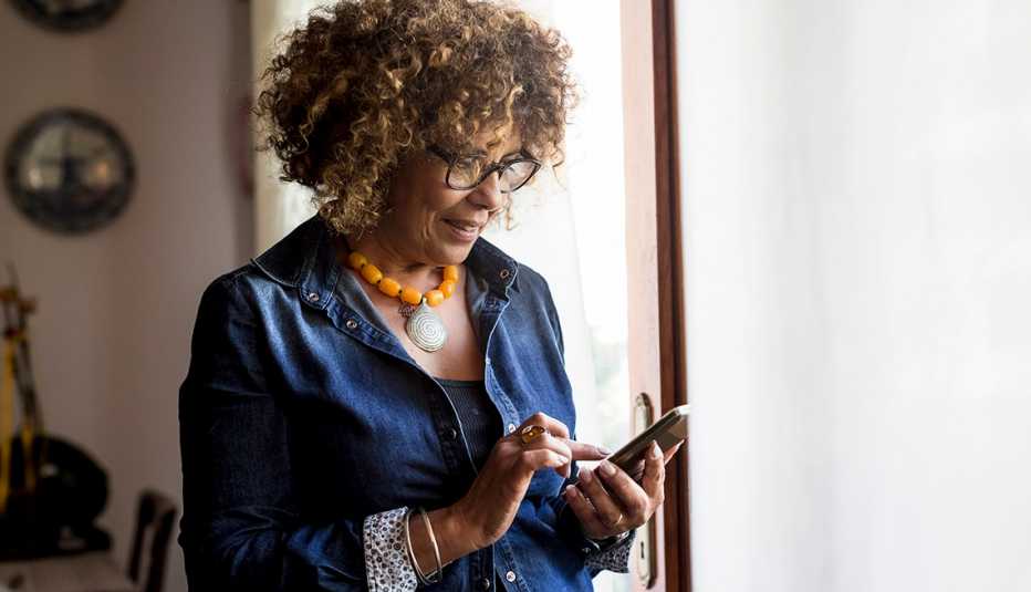 Mujer mira su teléfono inteligente cerca de una ventana