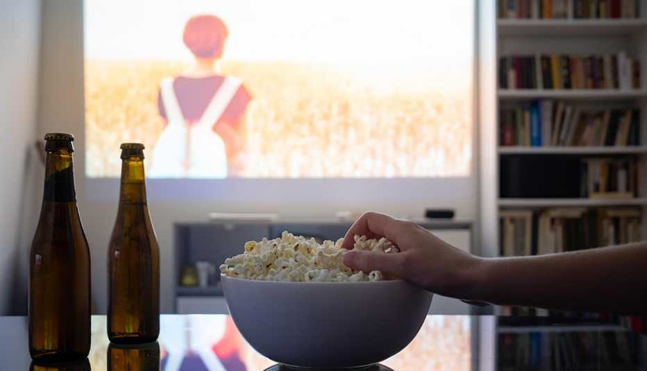 Mano de una persona busca un tazón de palomitas de maíz