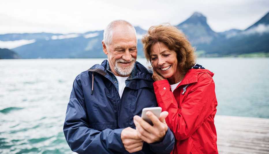 Un hombre y una mujer miran un teléfono mientras están parados en un muelle