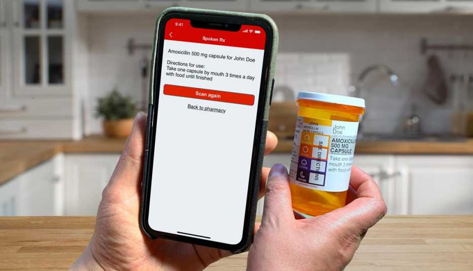 Persona sostiene un teléfono junto a una botella de medicamentos recetados