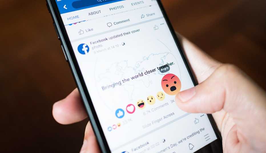 Un usuario de Facebook toca el botón de -enojado- en la aplicación de Facebook en el iPhone 7