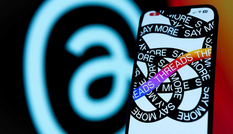 la pantalla de un teléfono inteligente muestra Threads con el símbolo de la aplicación al fondo