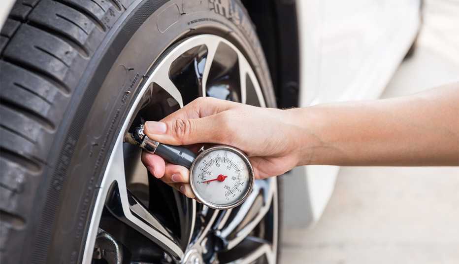 Persona revisa el nivel de presión de las llantas de su auto