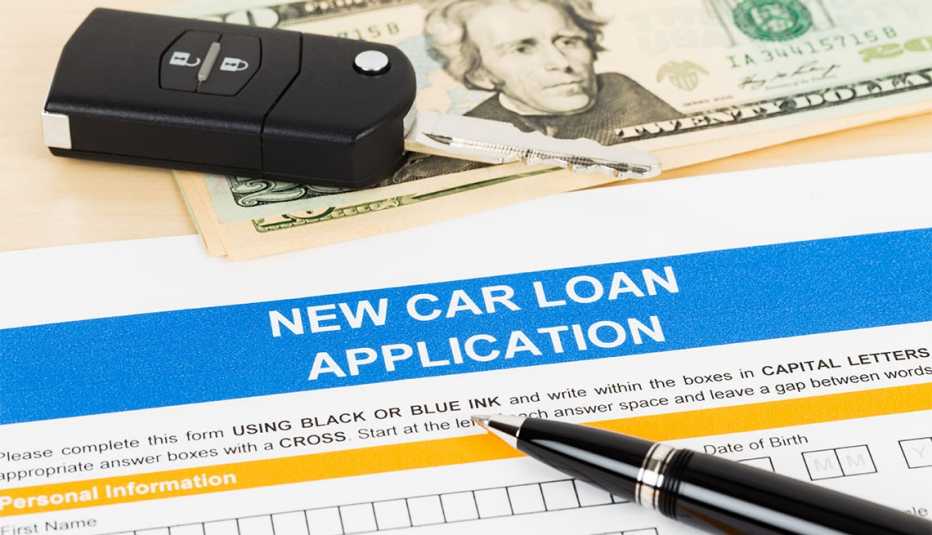 Solicitud de préstamo para comprar un auto y una llave de vehículo sobre un billete de 20 dólares
