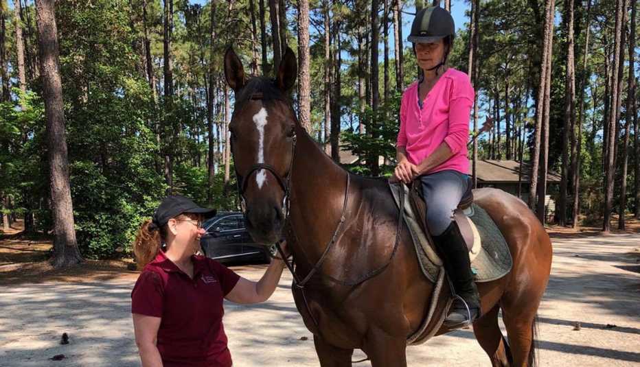 Holly Carter cabalgando un excaballo de carreras en un refugio al lado de una mujer que sostiene las riendas.