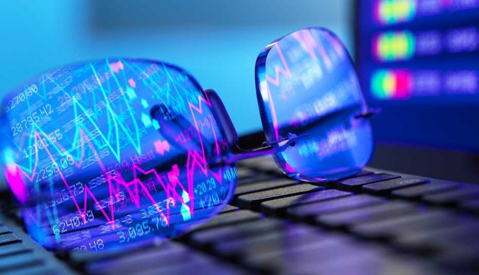 Lentes de lectura sobre una computadora reflejan cuadro de estadísticas de la pantalla.