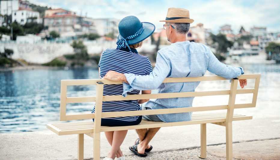Pareja sentada en una banca en Grecia frente al mar Mediterráneo