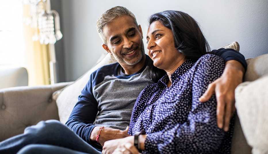 Una pareja feliz sentada en el sofá de su casa