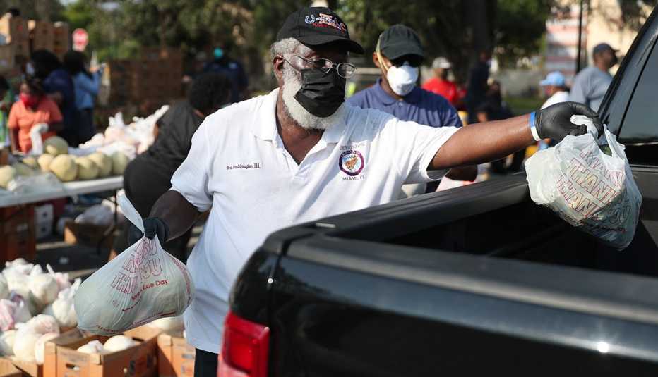 Un voluntario coloca bolsas de comida en una camioneta