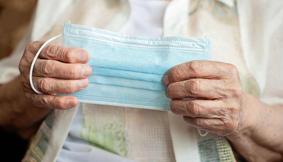 Manos de una mujer mayor que sostienen una mascarilla