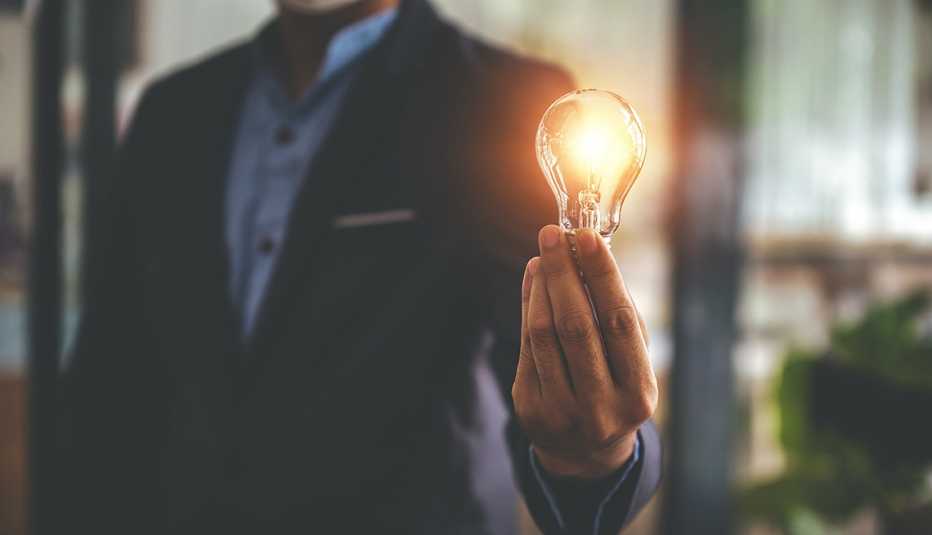 Hombre sostiene un bombillo con luz eléctrica
