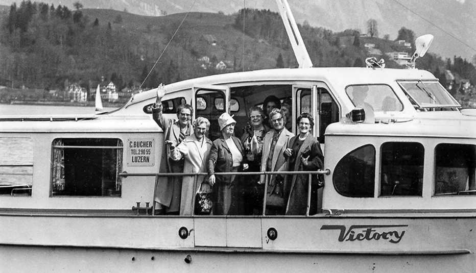 Personas saludan desde un bote en uno de los primeros viajes organizados por AARP.
