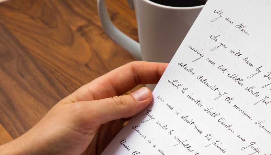 mano sostiene una carta escrita a mano con una letra clara