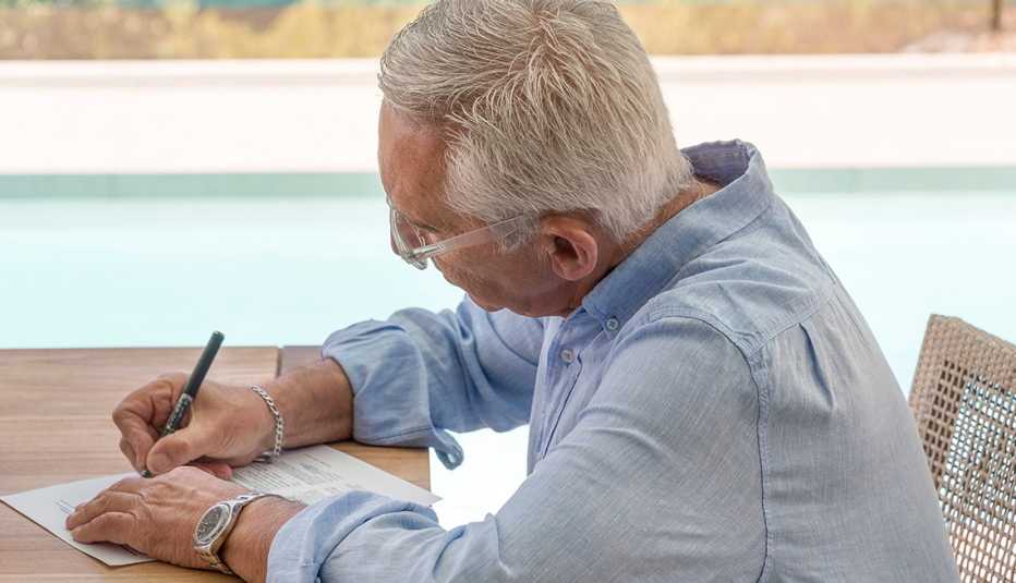 Un hombre escribe una nota sentado en un escritorio