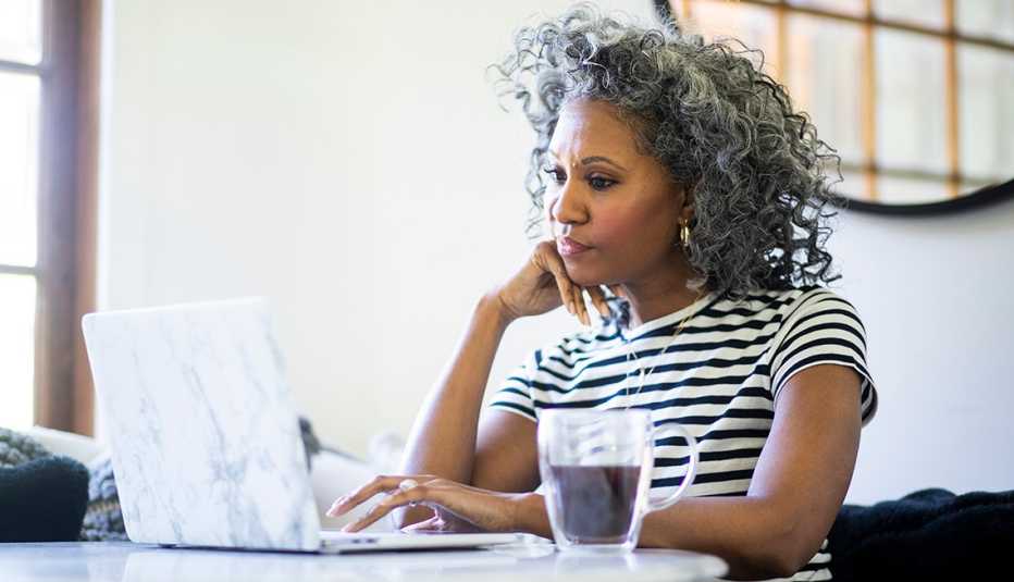 Una mujer en su casa usa una computadora portátil