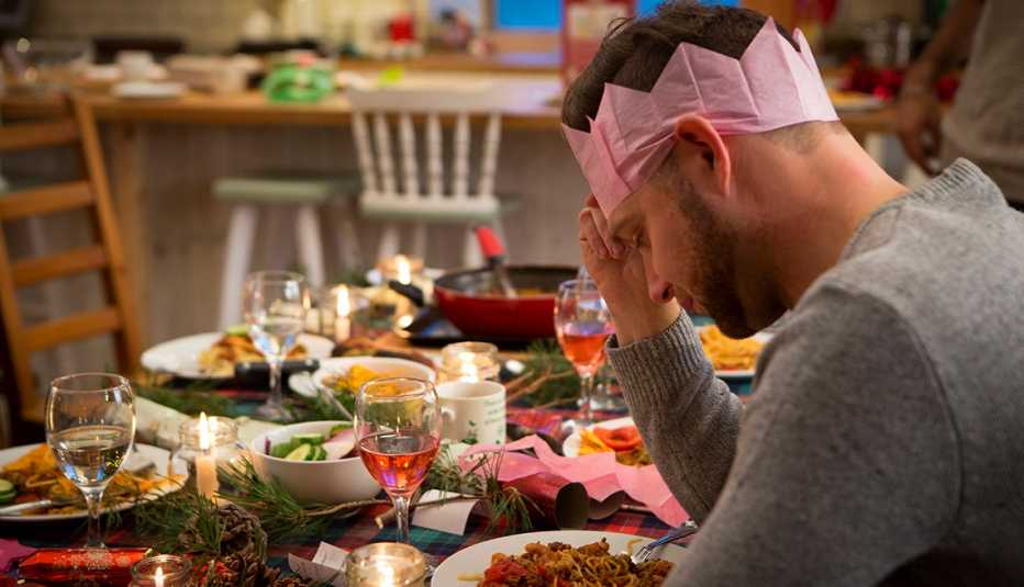  Hombre sentado en una mesa decorada para las fiestas luciendo solo y triste.