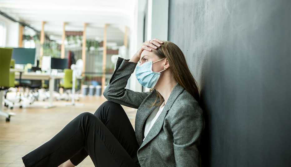 Mujer con máscara protectora facial luciendo preocupada en la oficina.