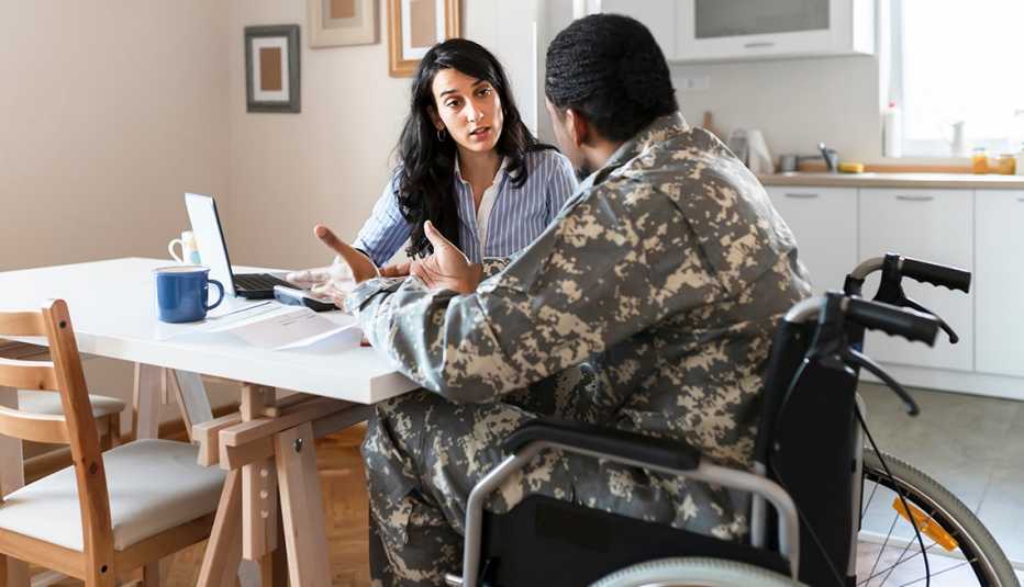 Un hombre con uniforme militar en silla de ruedas sentado en la mesa de la cocina.
