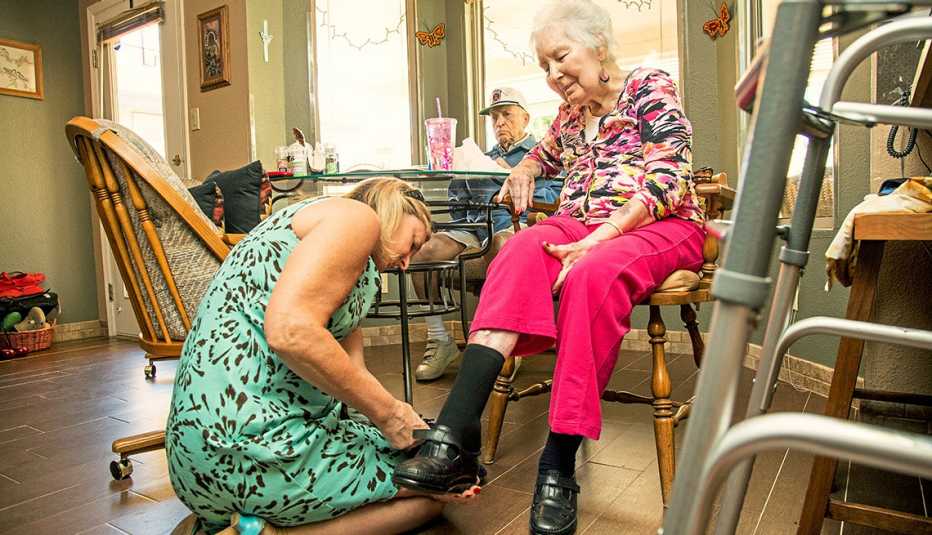 Amy Goyer ayudando a su madre a ponerse los zapatos mientras su padre observa