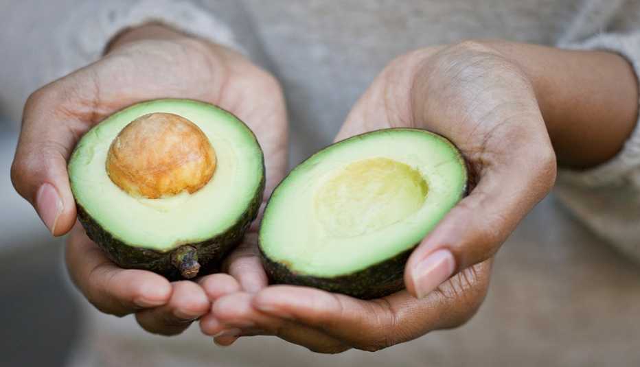 Mujer sosteniendo las dos mitades de un aguacate