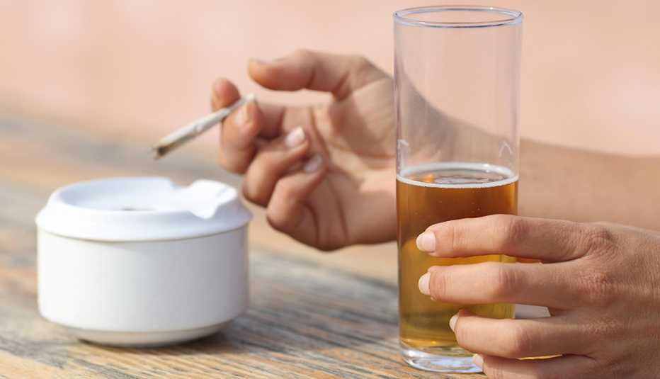 Manos de una mujer sosteniendo un cigarrillo y un vaso de cerveza