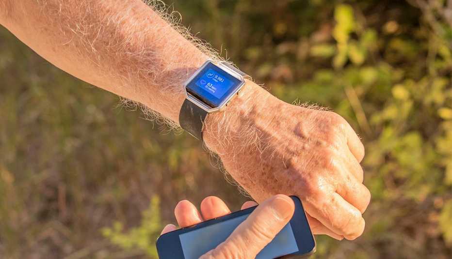 Hombre compara su reloj con su celular para verificar cuantos pasos ha dado