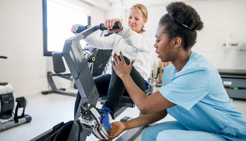 Una terapeuta ocupacional ayuda a una paciente a usar una bicicleta estática