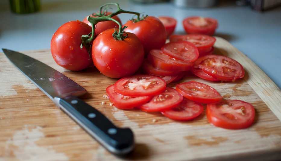 Tomates enteros y en rebanadas sobre un picador