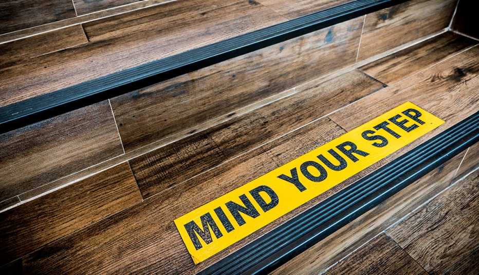 Rótulo en amarillo que advierte a las personas que tengan cuidado con el escalón