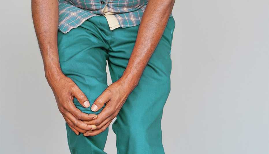 Un hombre se agarra la rodilla con ambas manos
