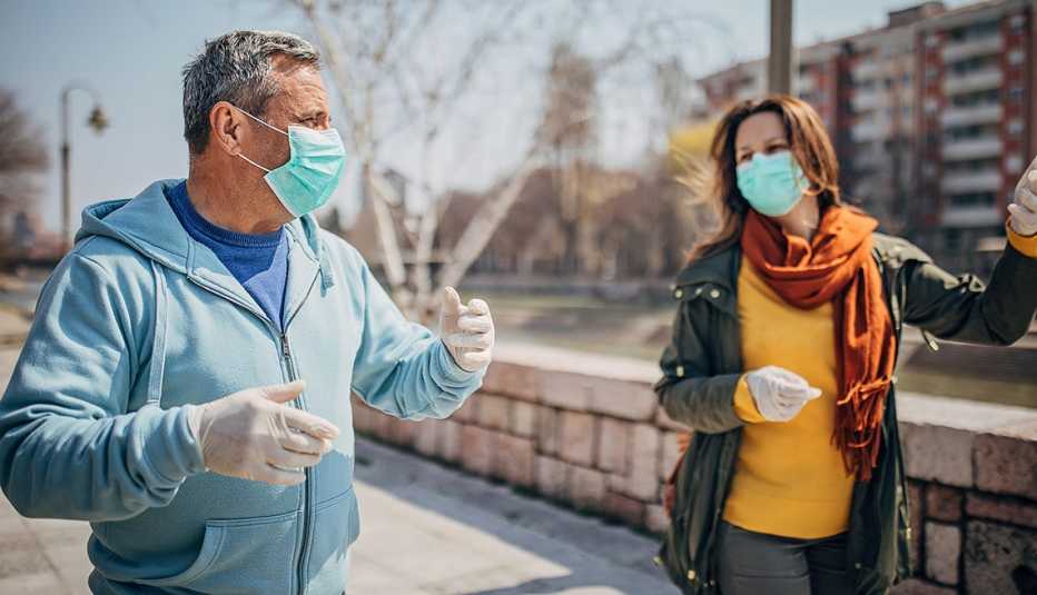 Una mujer y un hombre caminan al aire libre, ambos usando mascarillas