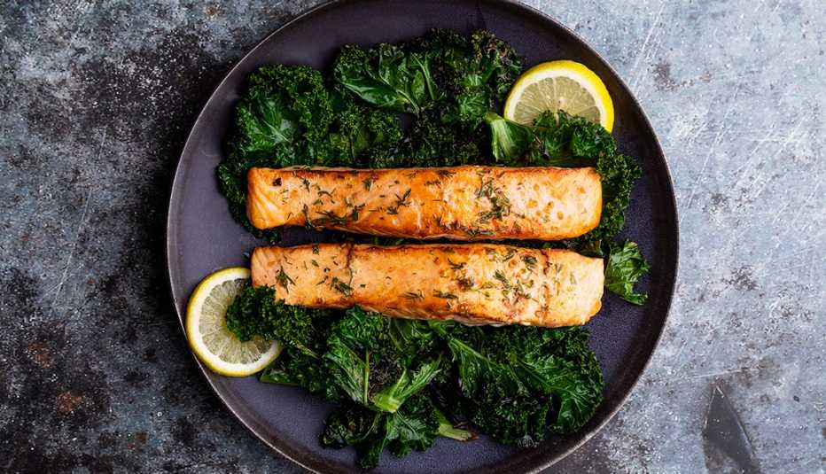 Filetes de salmón salteados con col rizada, eneldo y limón servido en un plato