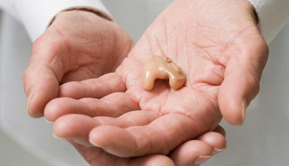 Un doctor sostiene un audífono en su mano