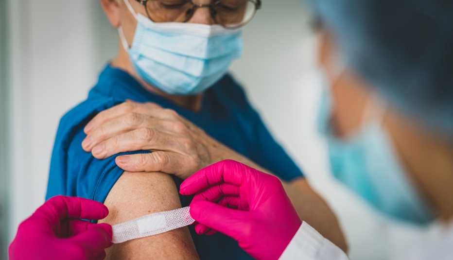 Proveedor médico coloca una tirita en el brazo de un paciente.