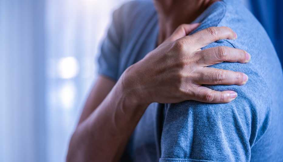 Un hombre con una mano en su hombro en señal de dolor