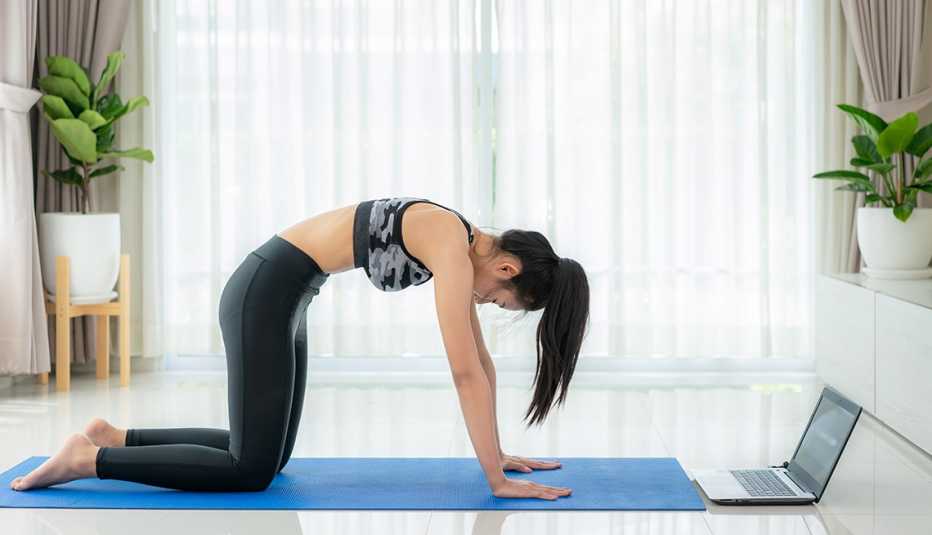 Una mujer con sus rodillas y manos en el piso forma un arco con su espalda