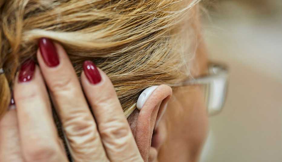 Una mujer recoge su cabello y se puede observar su audífono