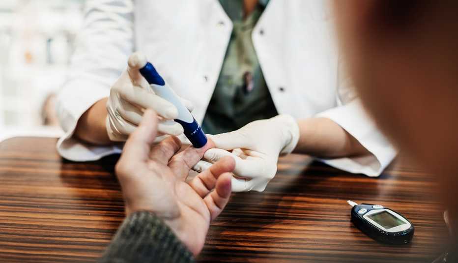 Un médico revisa el nivel de azúcar de un paciente
