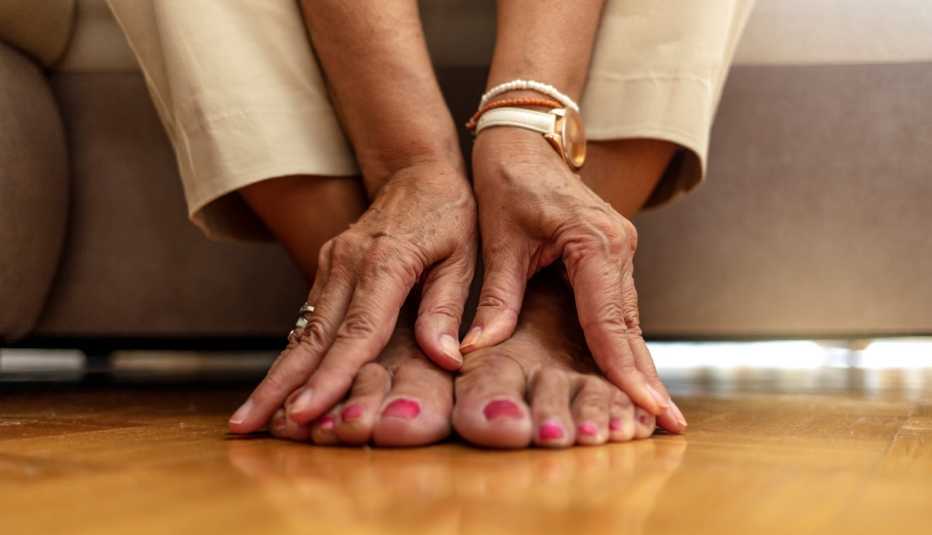 Una mujer masajea sus pies con ambas manos