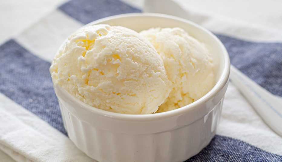Helado de vainilla en un platito pequeño sobre una mesa.