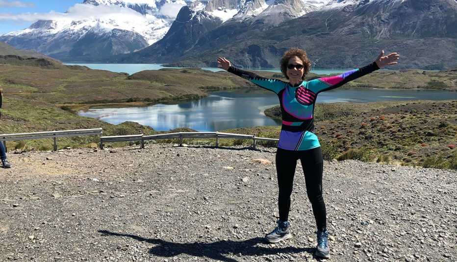 Una mujer abre sus manos ante un paisaje de montañas nevadas y un lago