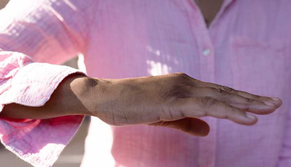 Una mujer sostiene su mano paralelo al piso en frente de sí misma