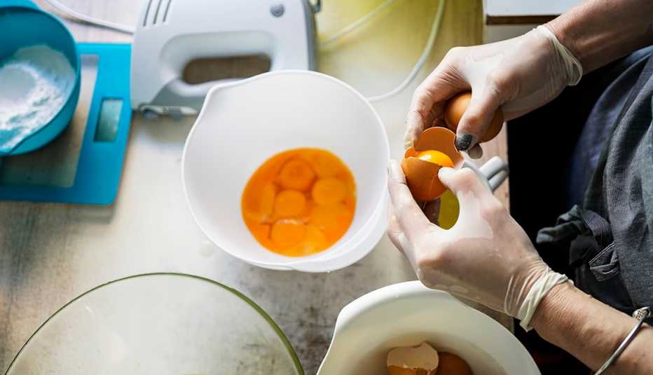 Un hombre abre varios huevos en un envase