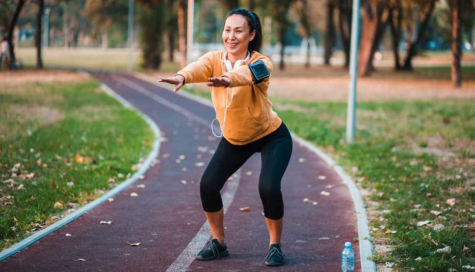 Una mujer de mediana edad haciendo sentadillas en un parque al aire libre