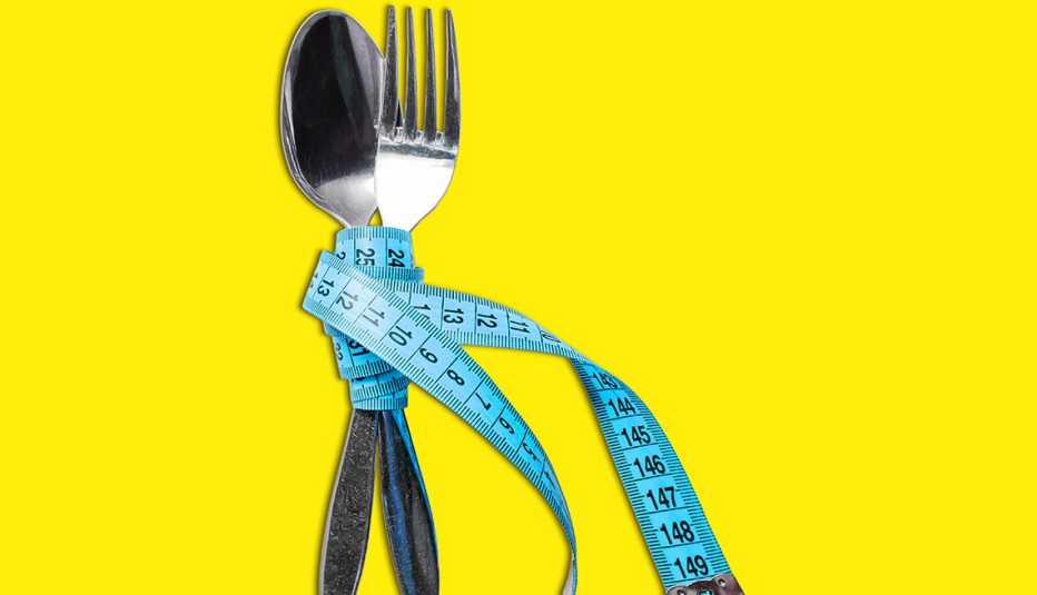 Una cuchara y un tenedor amarrados con una cinta de medir